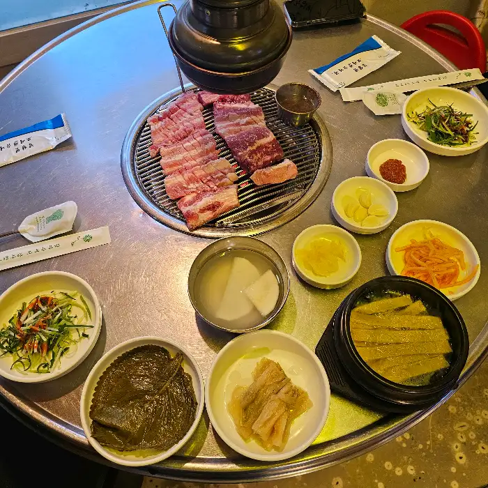 테이블 위에 놓인 푸짐한 고기와 다양한 밑반찬들, 그리고 술병