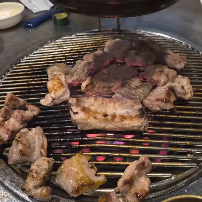 연탄불 위에서 노릇하게 익어가는 돼지고기 조각들