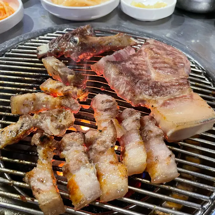 연탄불 위에서 익어가는 돼지고기, 겉면은 바삭하고 속은 촉촉해 보인다
