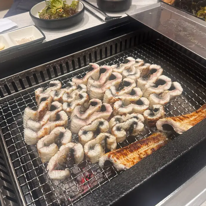 그릴 위에서 먹음직스럽게 익은 장어 조각들