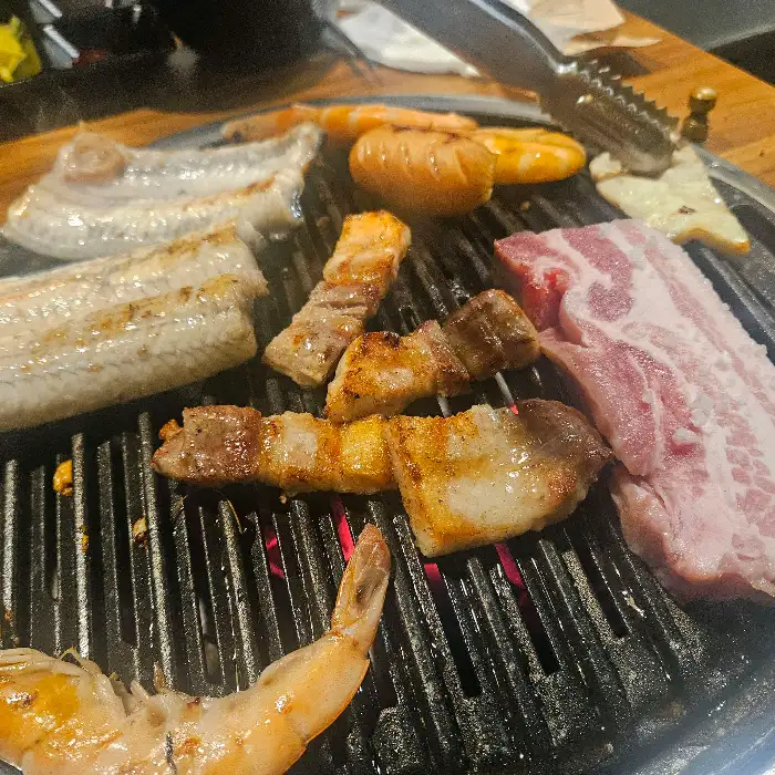 숯불 위에서 맛있게 구워지고 있는 장어, 소고기, 새우