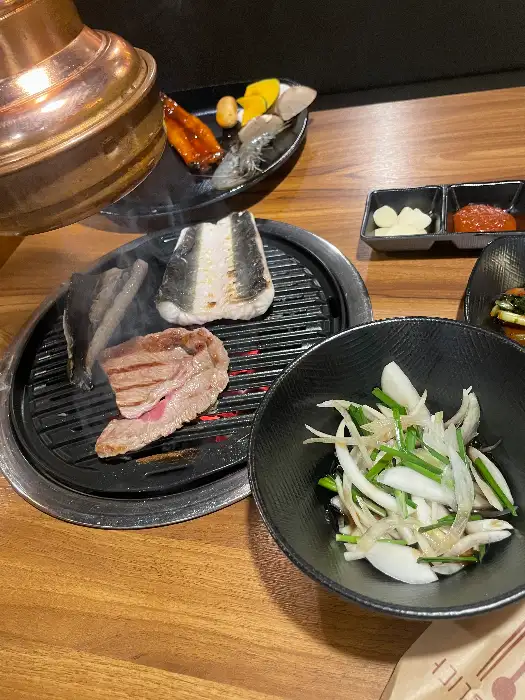 숯불 위에서 구워지고 있는 장어와 소고기, 그리고 곁들임 찬
