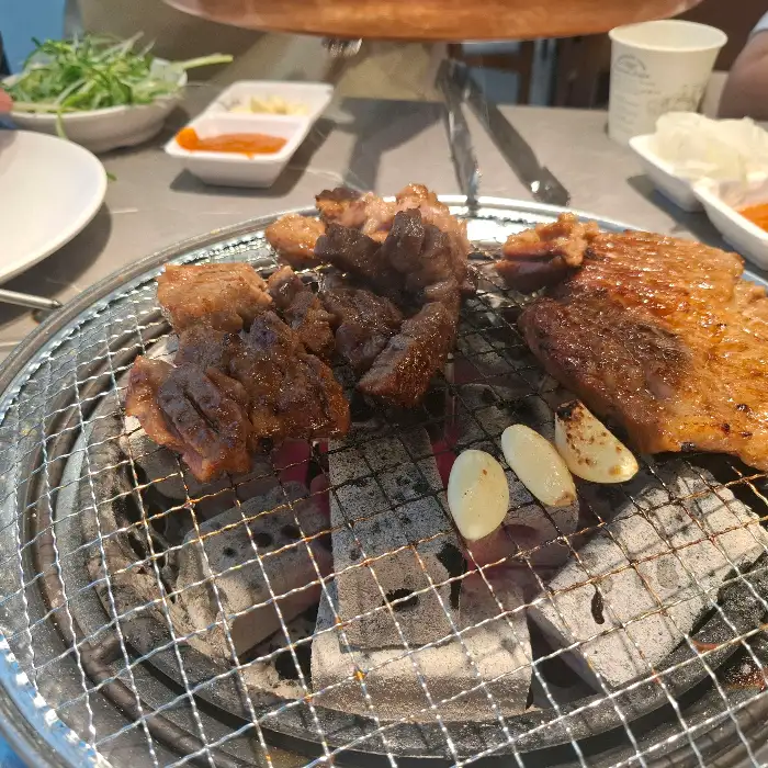 숯불 위에서 익어가는 다양한 고기와 마늘