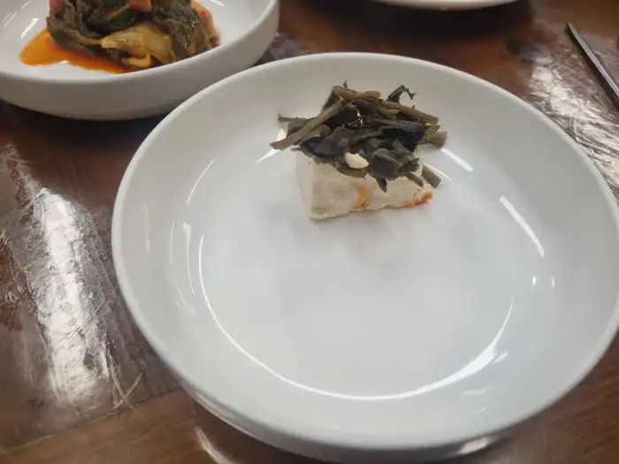 하얀 두부 조각 위에 양념된 나물이 올려진 모습