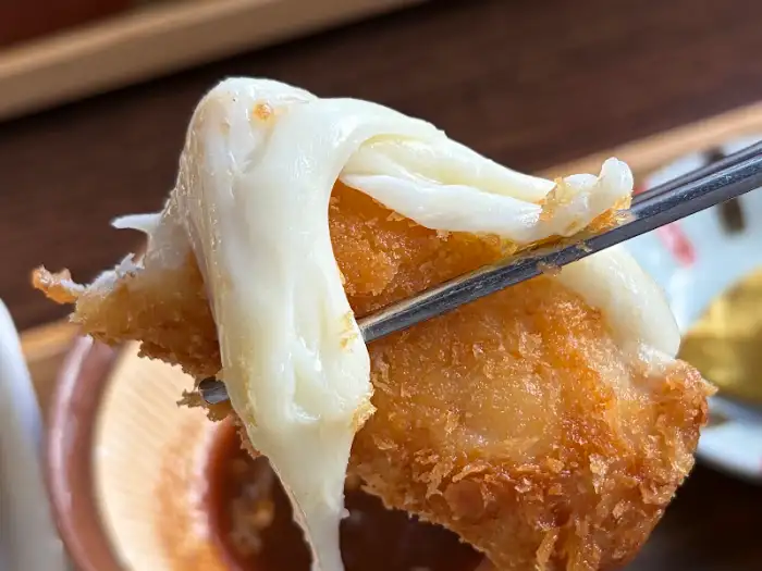 젓가락에 걸린 치즈 돈까스의 늘어나는 치즈
