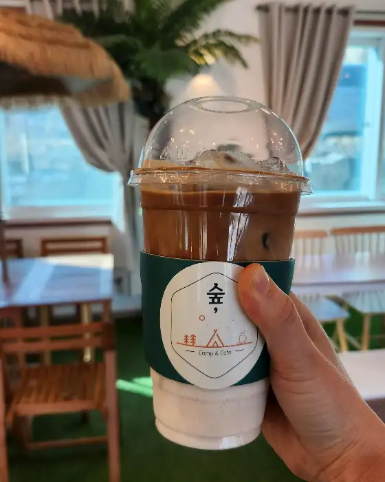 손에 들린 카페 컵홀더가 씌워진 음료
