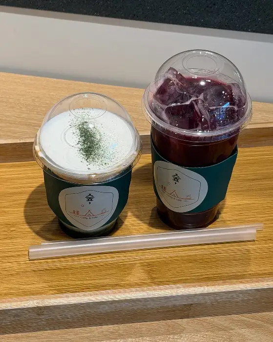 하얀 크림 위에 쑥가루가 뿌려진 음료와 보라색 음료