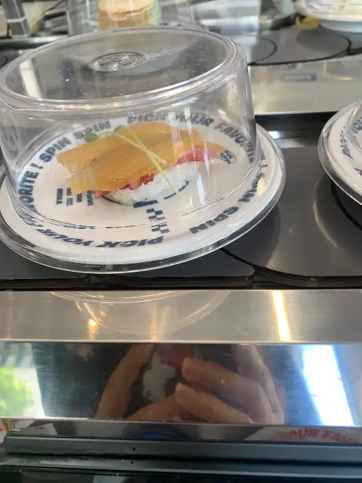 회전 레일 위에 투명 덮개로 덮인 초밥이 놓여 있다.