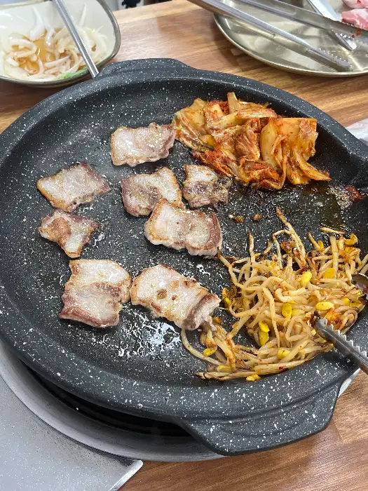 불판 위에 놓인 신선한 고기와 김치, 콩나물