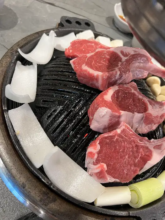 신선한 생양갈비 덩어리가 숯불구이판에 놓여있다.