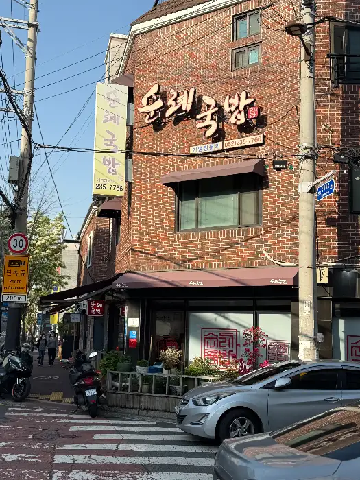 순례국밥 외부 모습. 붉은 벽돌 건물에 한글 간판이 달려있고, 앞에 차들이 주차되어 있다.