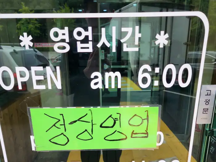 가게 출입문 유리창에 붙어 있는 영업 시간 안내문과 '정성 영업'이라고 쓰인 녹색 현수막.