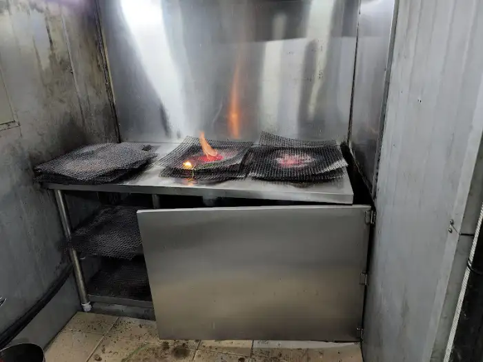 구워지고 있는 고기와 야채들이 있는 주방 내부 모습.