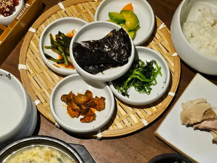 밥 위에 얹어진 김, 그리고 젓갈과 채소들이 담긴 그릇들.