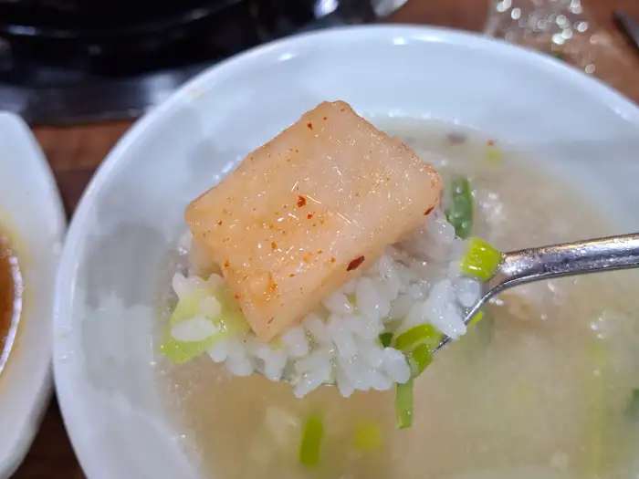 숟가락에 밥과 도가니 한 점, 파채가 함께 담겨 있다.