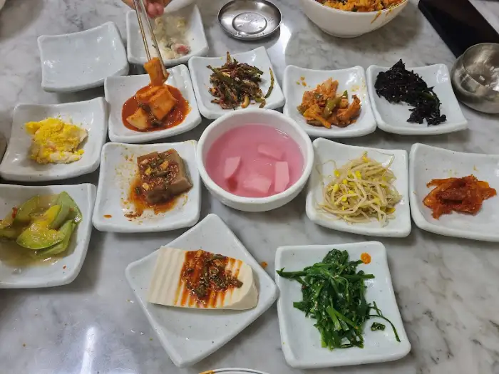 정갈하게 차려진 다양한 밑반찬과 핑크색 국물이 담긴 그릇을 보여주는 모습