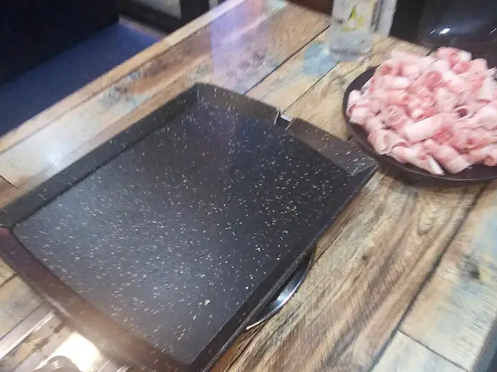 테이블에 놓인 대패 삼겹살 불판과 고기