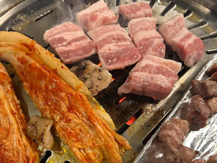 불판 위에서 맛있게 익어가는 삼겹살과 김치