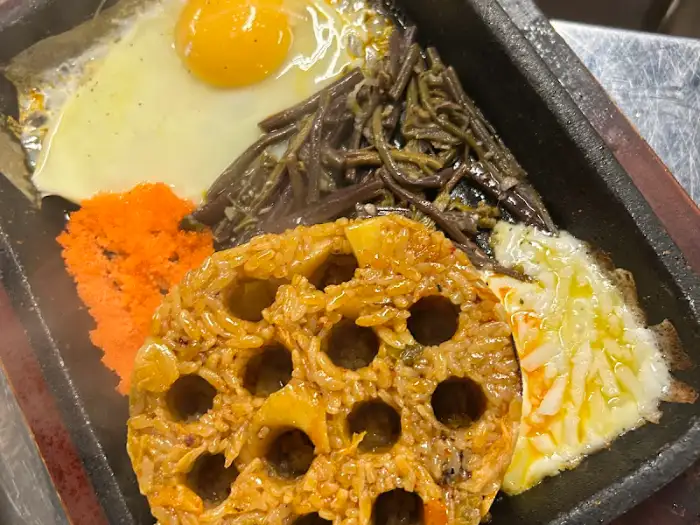돌판에 담긴 볶음밥과 계란 프라이, 채소