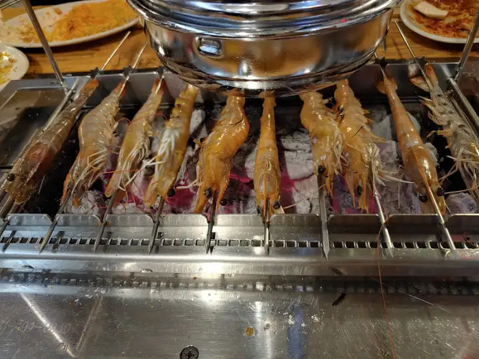 숯불 위에서 노릇하게 구워지고 있는 여러 마리의 새우 꼬치