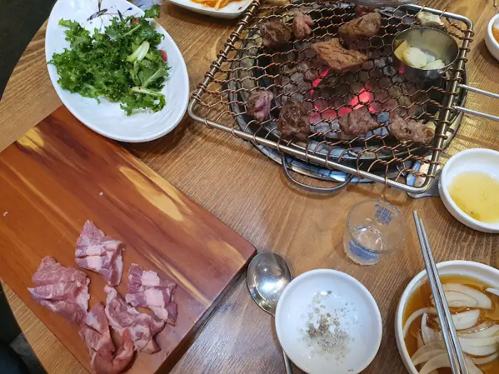 테이블 위 차려진 다양한 음식과 숯불 위 고기