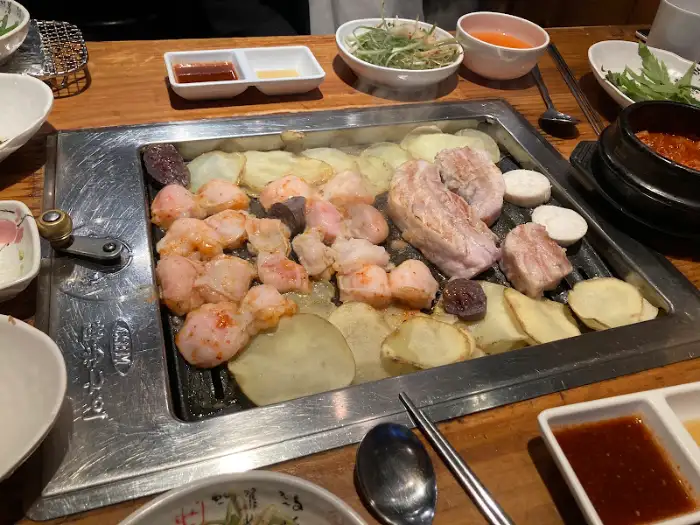 불판에 삼겹살, 대창, 감자슬라이스가 함께 익고 있는 모습