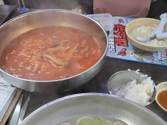 김치와 함께 제공되는 붉은 육수의 칼국수