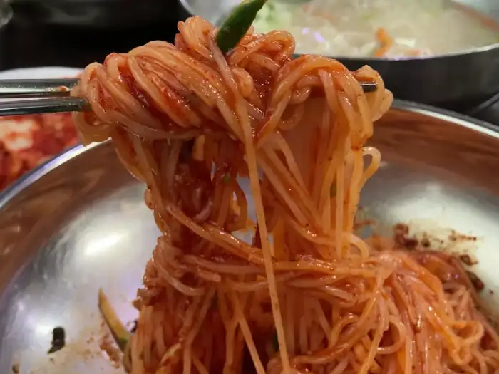 젓가락으로 집어 올린 붉은 양념의 비빔국수