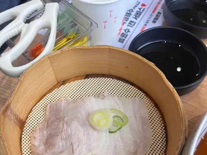 나무 찜통에 담긴 먹음직스러운 수육 한 점
