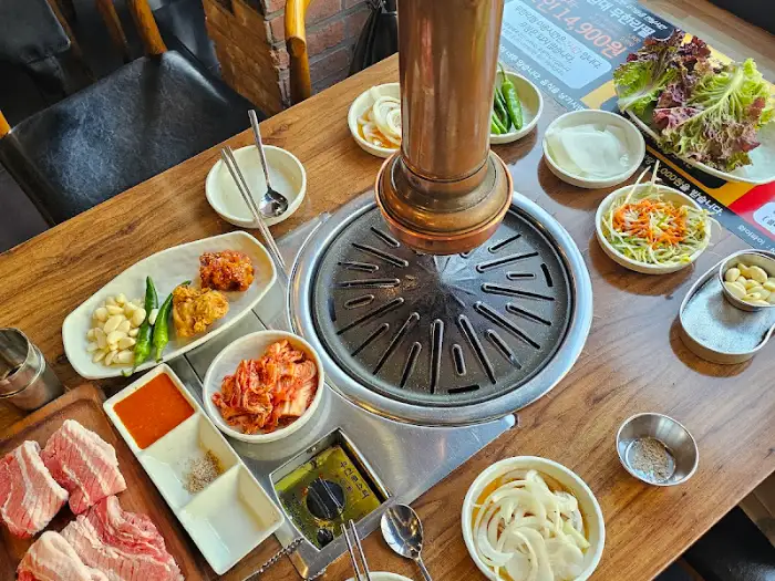 테이블 위 고기 불판과 다양한 반찬들