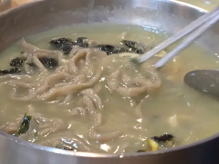 김이 모락모락 나는 보말 칼국수 그릇과 젓가락