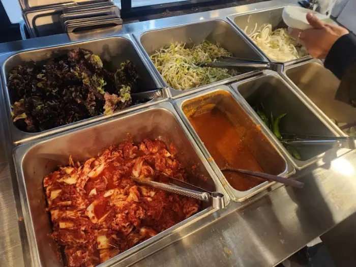 다양한 쌈 채소와 김치, 콩나물 무침 등이 담긴 용기