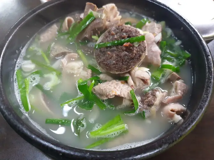 순대국밥 클로즈업 사진, 순대와 고기, 파가 푸짐하게 담겨 있다.