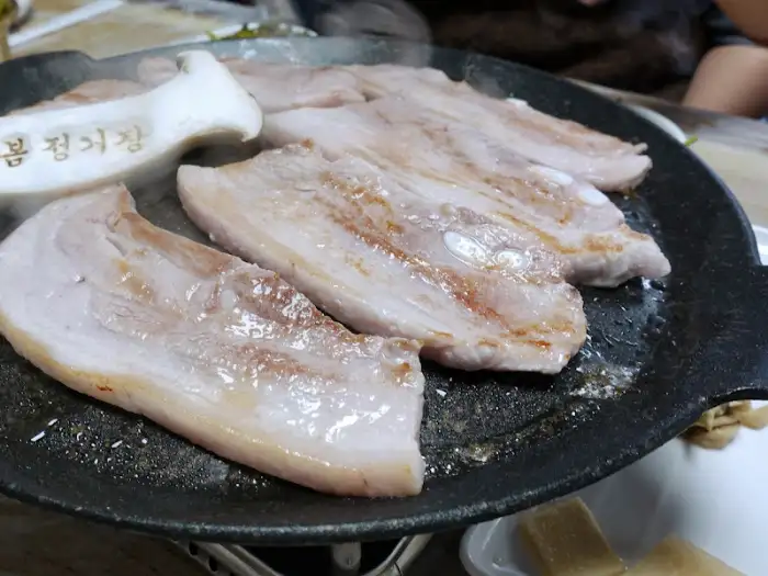 팬 위에서 익어가는 삼겹살과 미나리