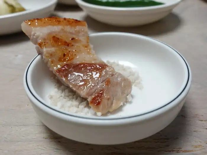 소금에 찍어 먹는 잘 구워진 삼겹살 한 점