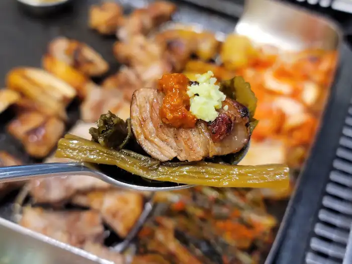 갓김치 위에 올려진 삼겹살 한 점