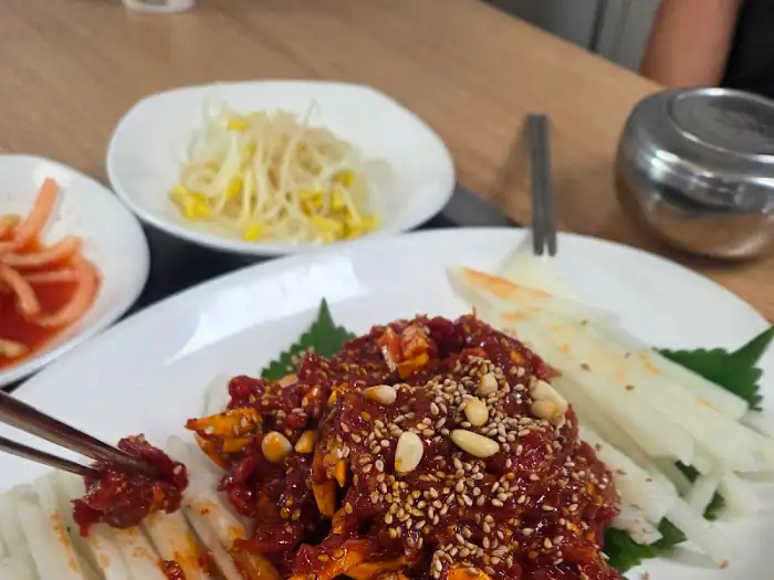 집게로 육회 한 점을 집어 드는 모습