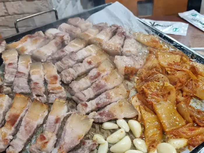 삼겹살과 묵은지, 마늘이 함께 구워지고 있는 불판 모습