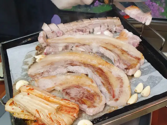 불판 위에 올라간 삼겹살과 묵은지, 마늘