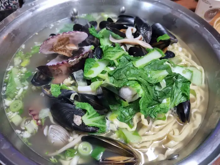 푸짐한 해물 칼국수. 조개와 채소가 가득 담겨 있다.