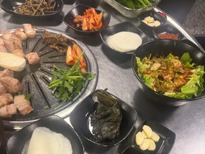 다양한 반찬과 흑돼지가 올려진 불판