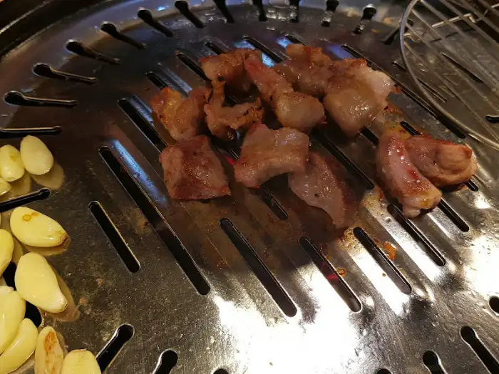 다양한 부위의 돼지고기가 숯불 위에서 익어가는 모습