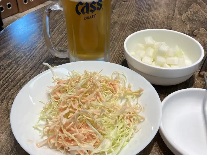 샐러드와 맥주, 그리고 치킨무가 함께 놓여 있는 테이블