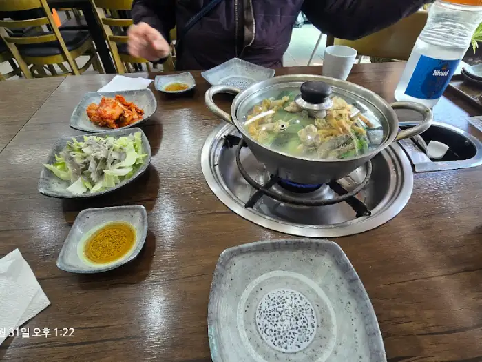 식탁 위 만두전골 냄비와 반찬들