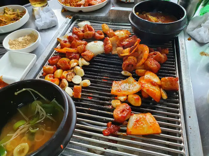 돼지 막창과 곁들임 채소가 불판 위에서 구워지고 있는 모습.