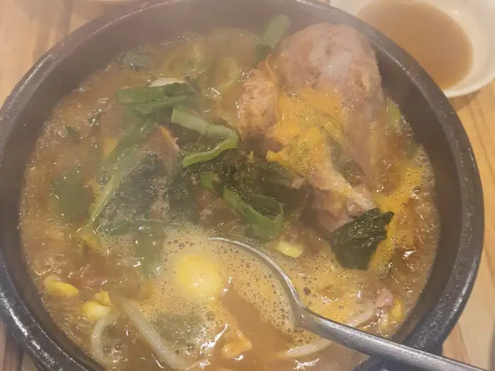뚝배기 감자탕에 큼직한 뼈가 두 개 들어있는 모습