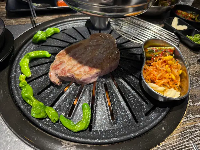 불판 위에서 지글지글 익어가는 삼겹살과 곁들임 고추