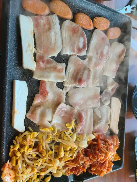 불판 위에서 익어가고 있는 돼지고기와 곁들임