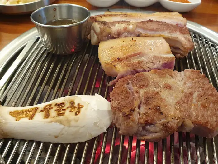 두툼하게 썰린 삼겹살과 목살이 숯불 위에서 노릇하게 익어가고 있습니다. 비계 부분도 먹음직스럽게 보입니다.