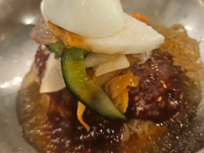 그릇 가득 담긴 비빔냉면 위로 계란, 오이, 배채 등이 보기 좋게 올려져 있습니다. 매콤해 보이는 양념장이 침샘을 자극합니다.